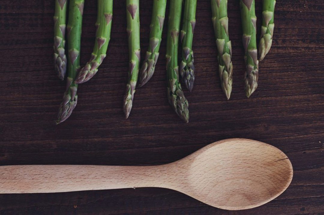 Grüner Spargel mit einem Kochlöffel